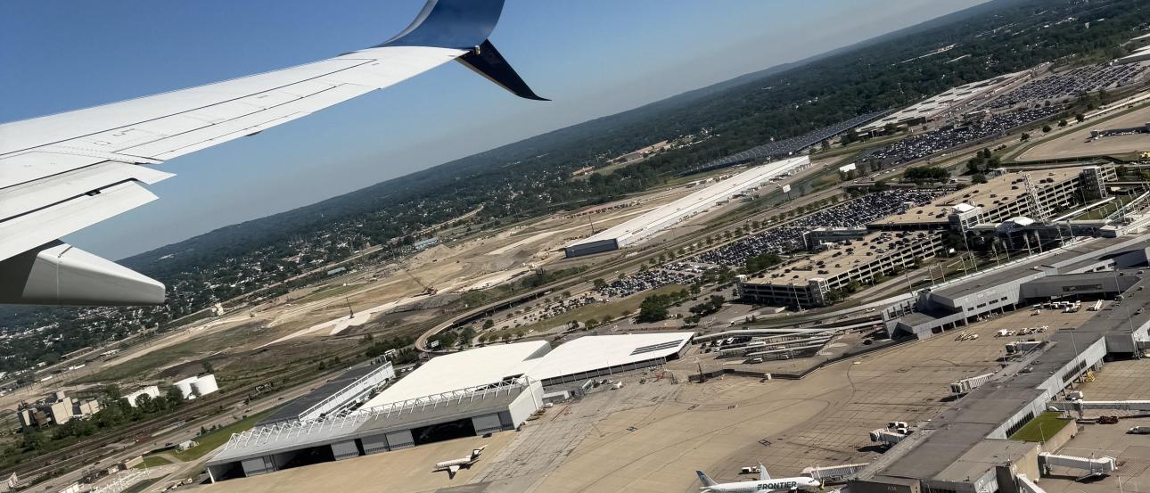 A view from the window of an airplane showing an aerial view of the Cleveland Hopkins airport on a sunny day with crystal clear skies.