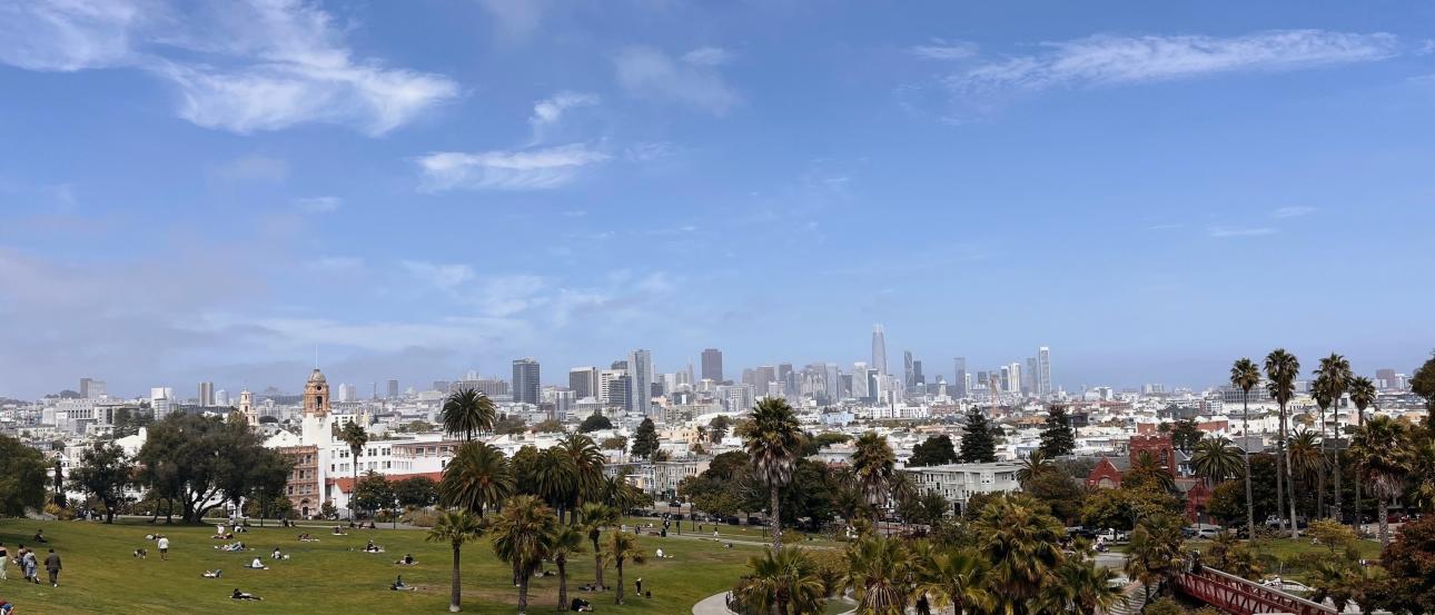 Picnic-goers enjoy the city skyline on a sunny day at San Francisco's Dolores Park.