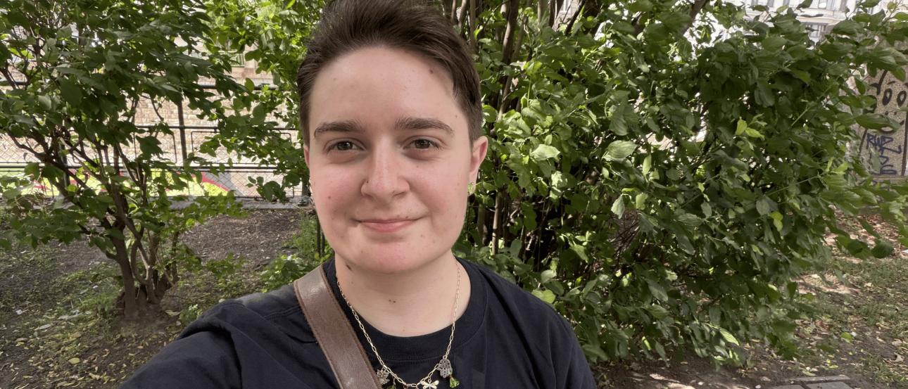 A selfie of the author on a bench with some trees in the background.
