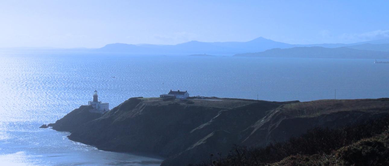 Cliffside lighthouse overlooking the sea under a clear blue sky. This alt text was added with Al; accuracy may vary.