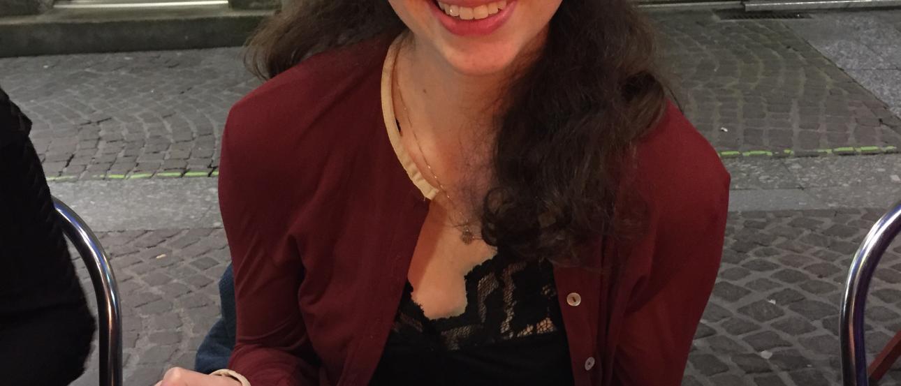 Smiling woman holding a large plate with a crepe, outdoor cafe setting. This alt text was added with Al; accuracy may vary.