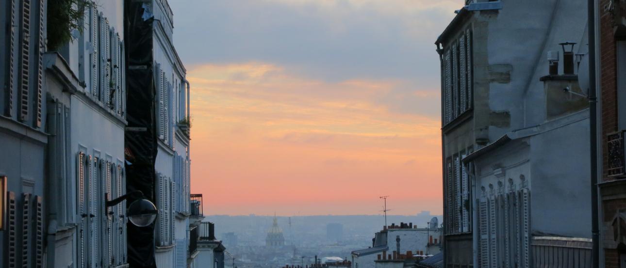 1. Archway view of distant cityscape under blue sky.
2. Ferris wheel silhouette at sunset, city skyline.
3. Narrow street at sunset with pastel sky. This alt text was added with Al; accuracy may vary.