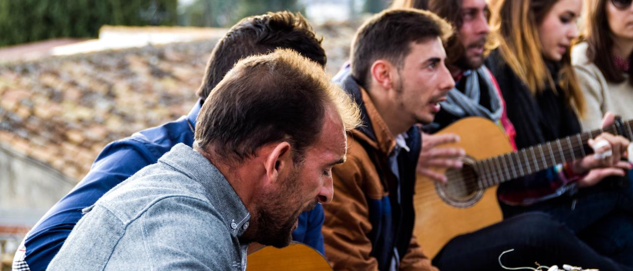 Musicians playing acoustic guitars outdoors, focused and engaged. This alt text was added with Al; accuracy may vary.