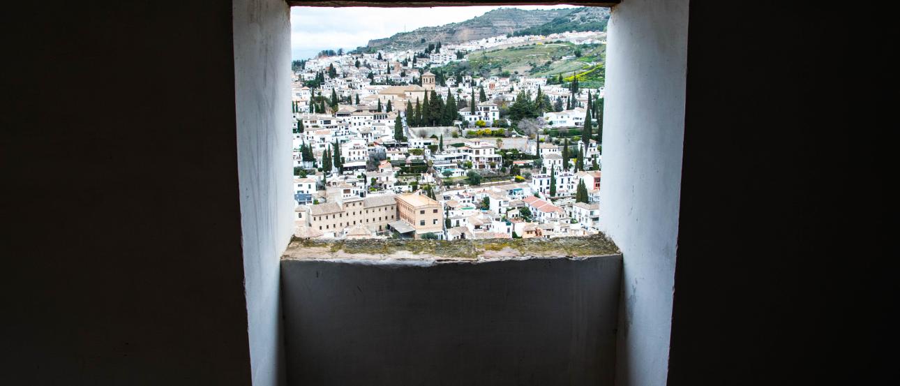View through a window, overlooking a city with greenery and hills in the distance. This alt text was added with Al; accuracy may vary.