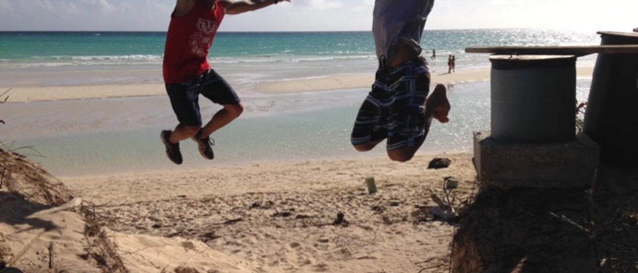 River view of London skyline with Big Ben and Parliament under cloudy sky.

Two people jumping joyfully on a sunny beach. This alt text was added with Al; accuracy may vary.