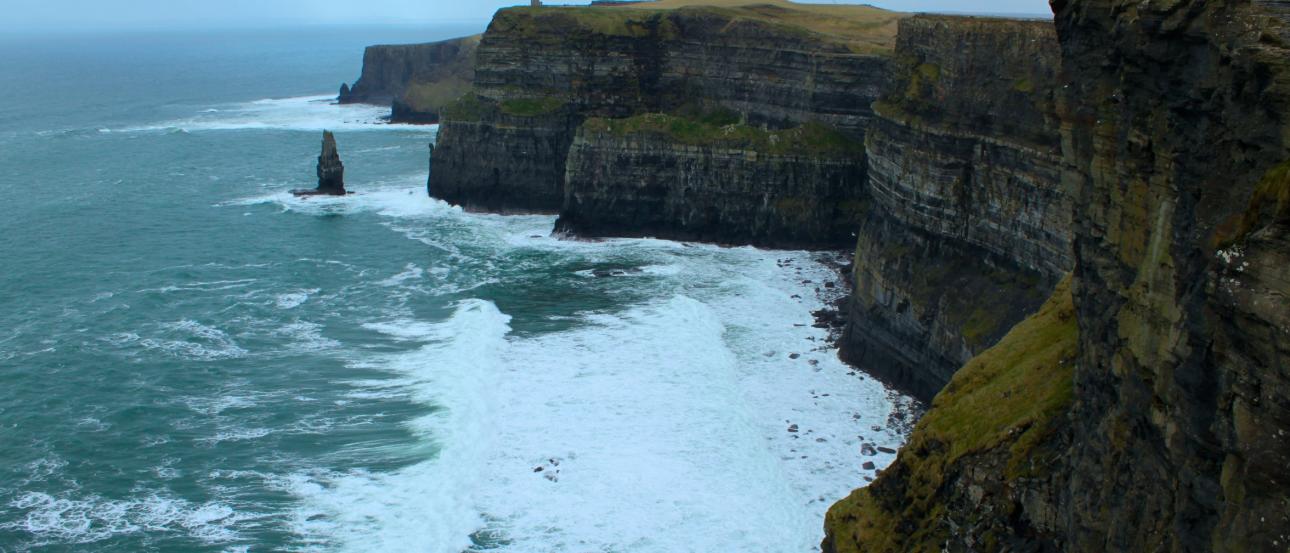 Ancient stone archway with three people smiling in foreground. This alt text was added with Al; accuracy may vary.