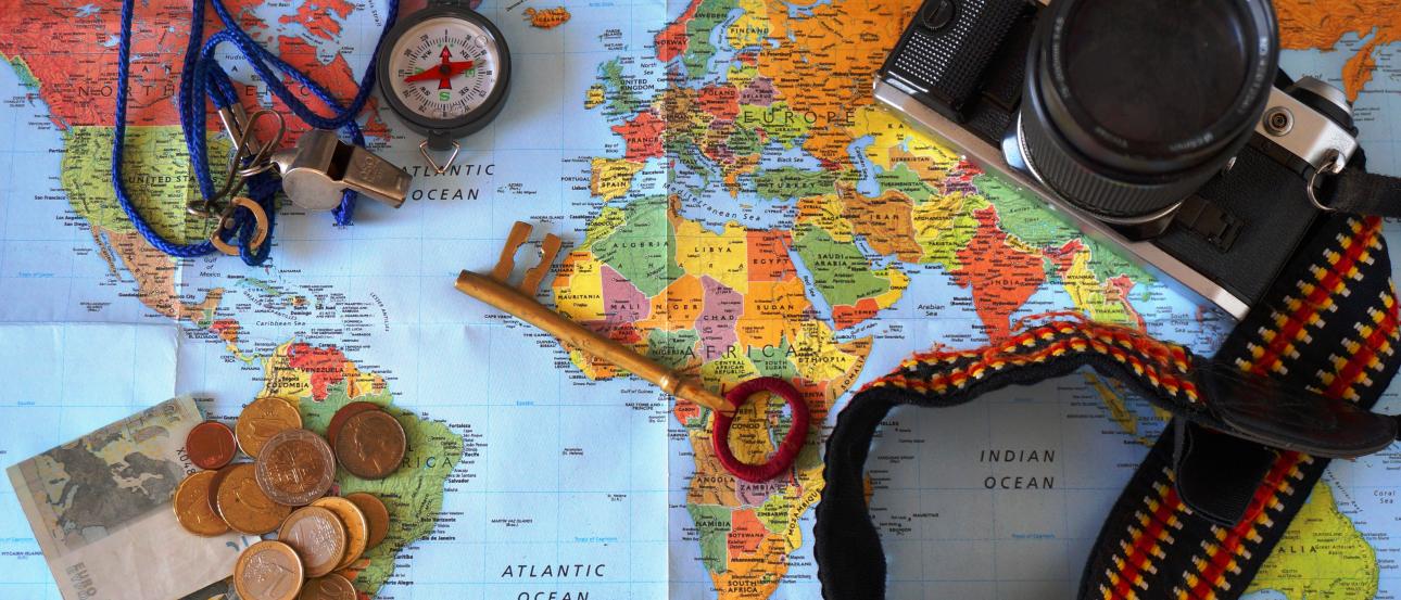 Map with camera, coins, compass, and a passport. This alt text was added with Al; accuracy may vary.