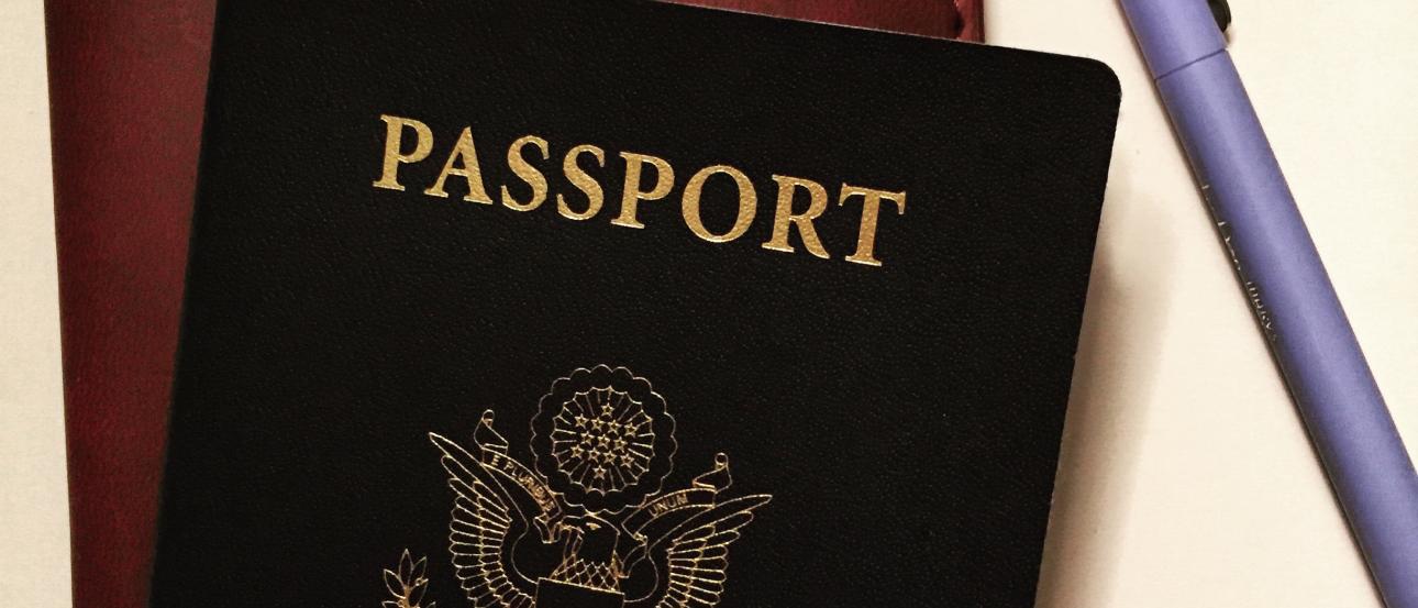 Crème brûlée in a white ramekin with caramelized top.

People posing with a large cat mascot in a public area.

Three people with guitars smiling under a bridge, one seated, with traffic cones nearby.

US passport and "bon voyage" notebook with a pen on a surface. This alt text was added with Al; accuracy may vary.