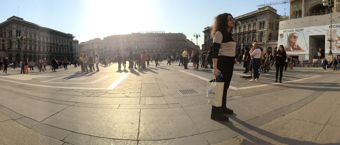 Historic square with people walking and buildings in the background under bright sunlight. This alt text was added with Al; accuracy may vary.