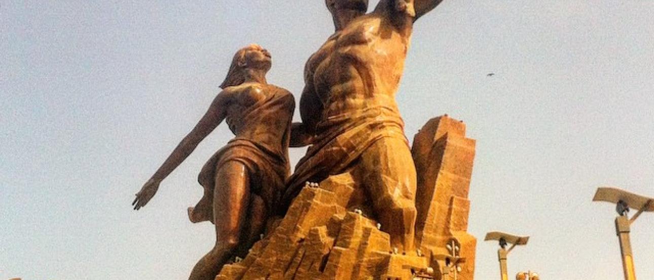 Bronze statue of a family on a large stone base with people walking up steps. This alt text was added with Al; accuracy may vary.