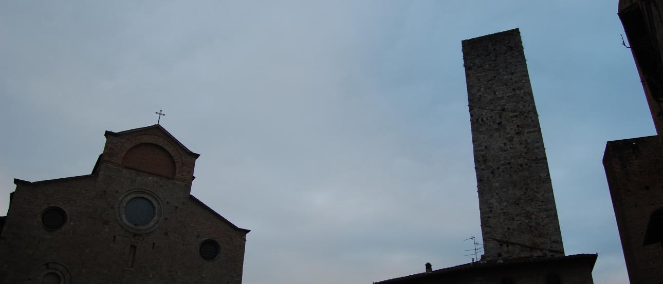 Rooftops of a European town with red tiles and chimneys under a hazy sky. This alt text was added with Al; accuracy may vary.