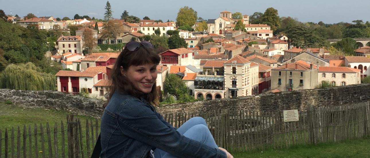 A person sitting on stone ruins with a view of Clisson village in the background. This alt text was added with Al; accuracy may vary.