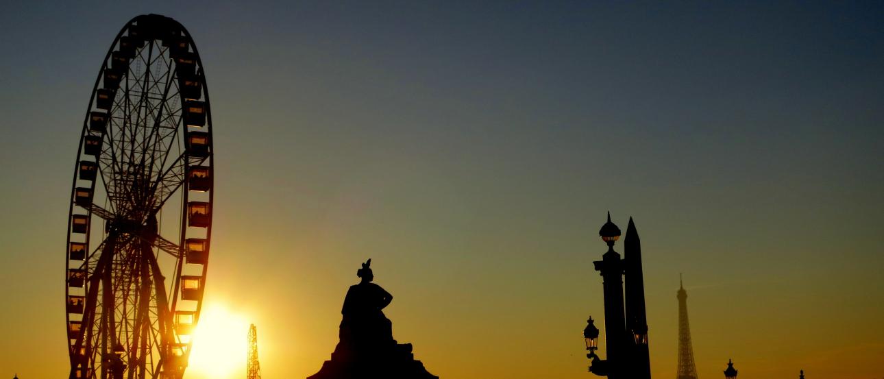 View through archway to gardens, a distant cityscape under a blue sky. This alt text was added with Al; accuracy may vary.