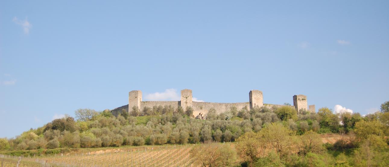Group of six people smiling by a riverside railing, with historic buildings in the background. This alt text was added with Al; accuracy may vary.