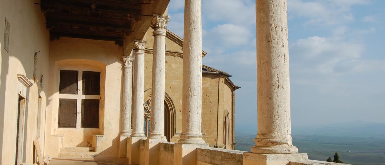 Elegant corridor with white columns, overlooking a vast landscape under a blue sky. This alt text was added with Al; accuracy may vary.