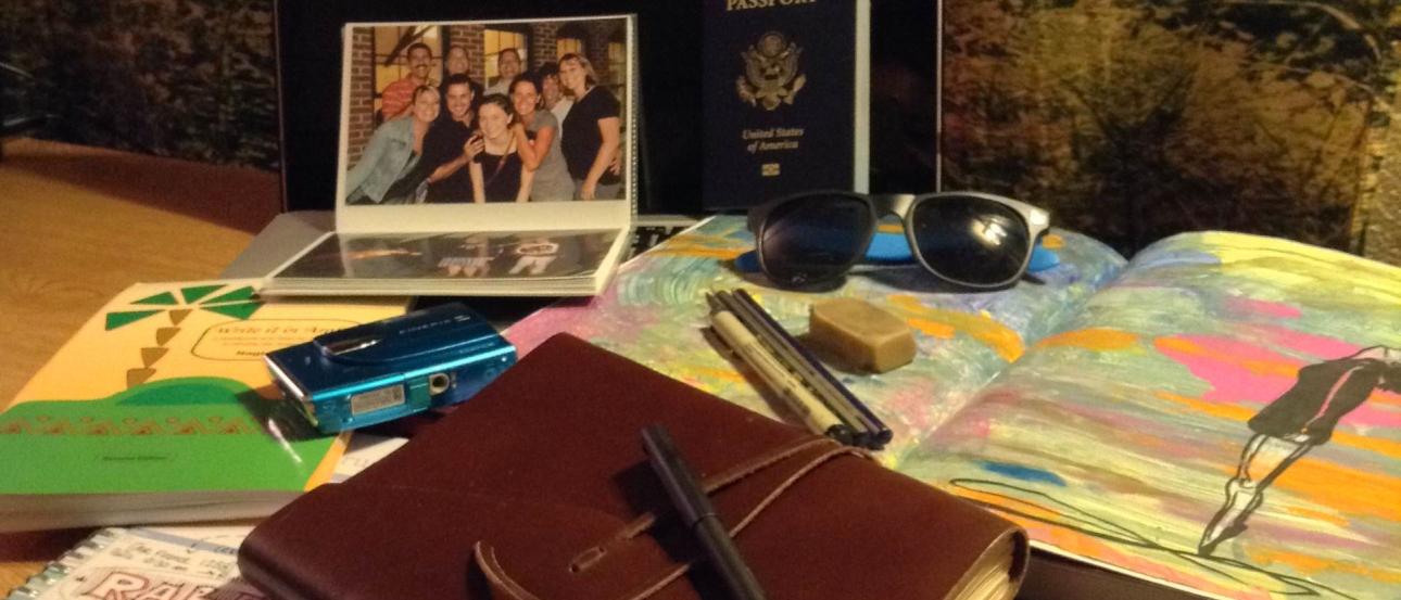 Travel essentials on a table: journal, map, passport, and family photo. This alt text was added with Al; accuracy may vary.