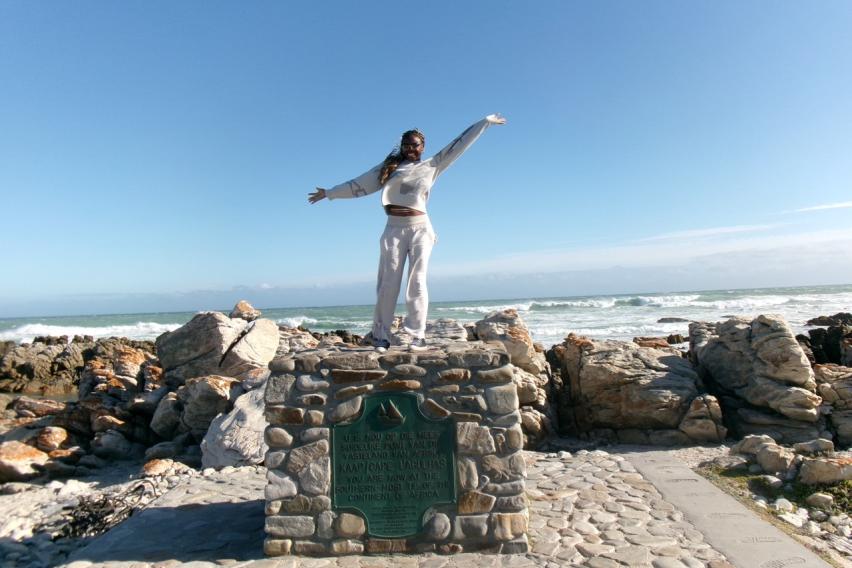 Picture of me on a structured pile of rocks with a plaque reading that where I am is Africa’s southernmost point. East of this is the Indian Ocean, and west is the Atlantic Ocean.