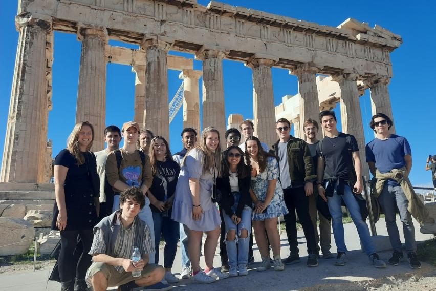 Group of people posing in front of the Parthenon under a clear blue sky. Athens field trip