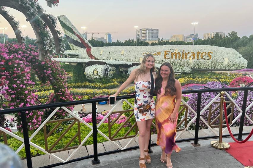 Two girls posing at Dubai Miracle Garden in front of a floral Emirates airplane display