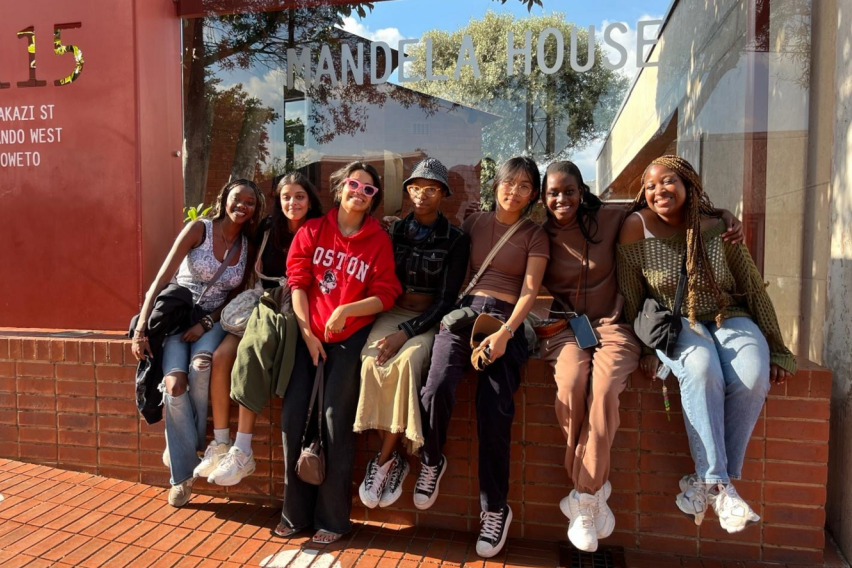 Group of students sitting outdoors smiling on a sunny day