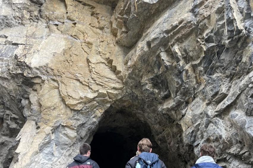 People entering a cave wearing backpacks