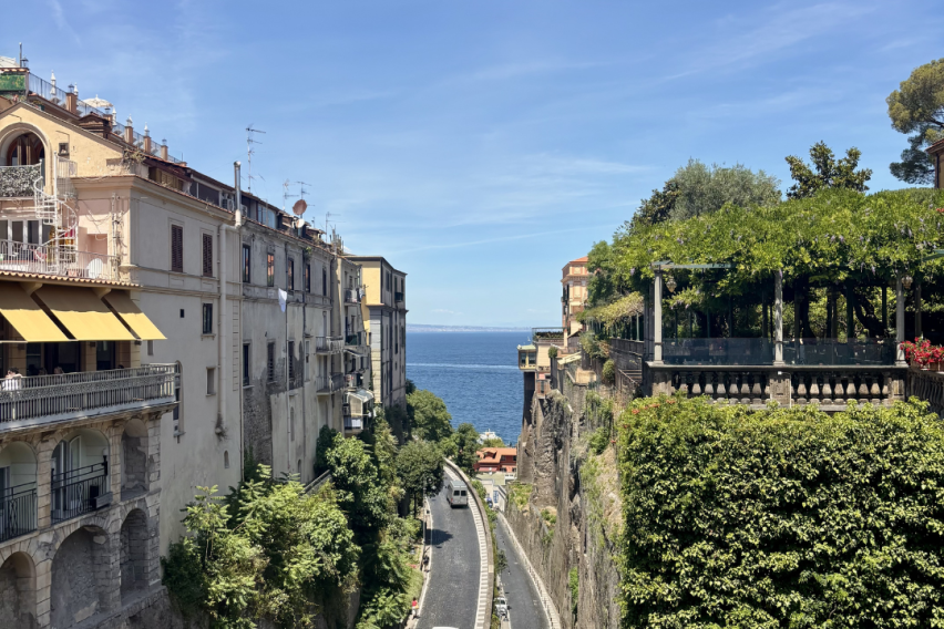 Two cliffs lining a road at the bottom with a view of the sea