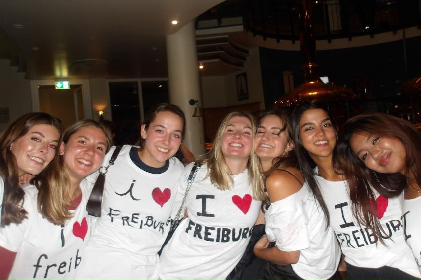 Seven girls smile and pose in homemade "I heart Freiburg" shirts.