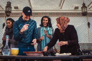 students laugh while cooking with their host mom in Rabat
