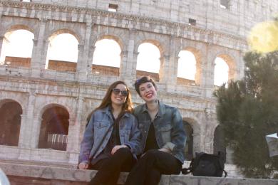 students smile for a photo on a sunny day in front of the Roman Colosseum