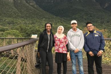 students on a bridge standing in front of mountain 
