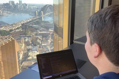 Intern at their computer with a view of Sydney's Harbour Bridge