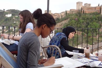 Three students in a painting class on the Granada Center patio.
