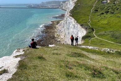 Students explore the rocky inclines off the coast of Dover on a sunny day.