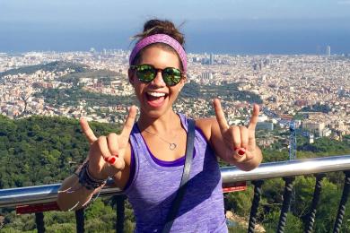 a student doing a "rock on" hand sign in front of a Barcelona city overlook
