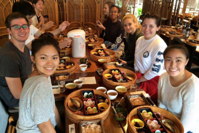 Students share a meal together in Tokyo. On the table are open bento boxes.