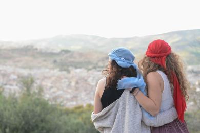Two students in Morocco wearing red and blue headscarves look out over the city.