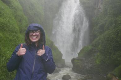 A student gives a thumbs-up in front of a waterfall in Quito, Ecuador.