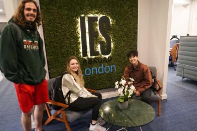 Three people sitting in front of IES Abroad London sign 