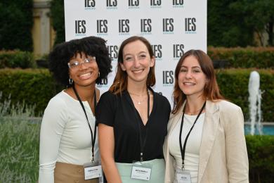 three internship students standing in front of backdrop with IES Abroad logo