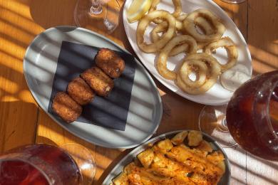 four glasses of Tinto de Verano and three plates of tapas: croquetas, calamari, and patatas bravas.