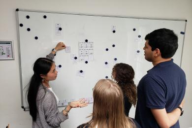 instructor teaching two students standing at a white board