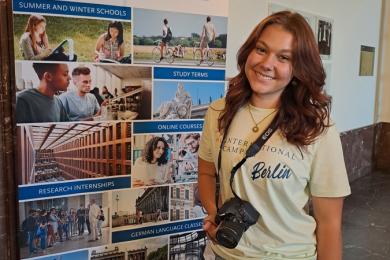 Woman holding a camera in the hand standing by  banner