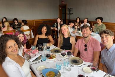 Group of students around a restaurant table with red wine and food