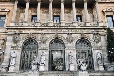 view of the front steps of greystone library with arches and columns and flag on top