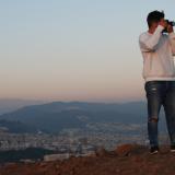 Christian Canizal holding up a camera in front of a sunset.