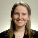 Young woman smiling, wearing a denim jacket against a gray background. This alt text was added with Al; accuracy may vary.