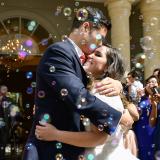 Justin and Monica at their wedding surrounded by guests blowing bubbles