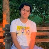 Avery Trinidad sitting on a bench outside in front of some trees. 