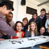 a diverse group of students looking at Chinese characters on a page