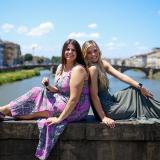 two girls sitting on the bridge and smiling in siena 